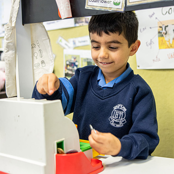 Holy Trinity Catholic Primary School Granville student behind toy cashier