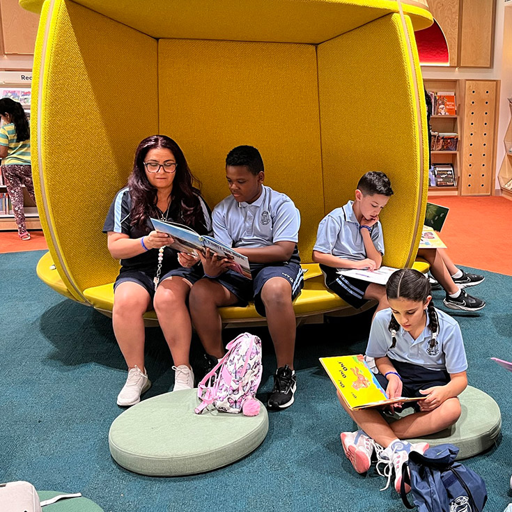 Teacher with students in the Holy Trinity Primary Granville library